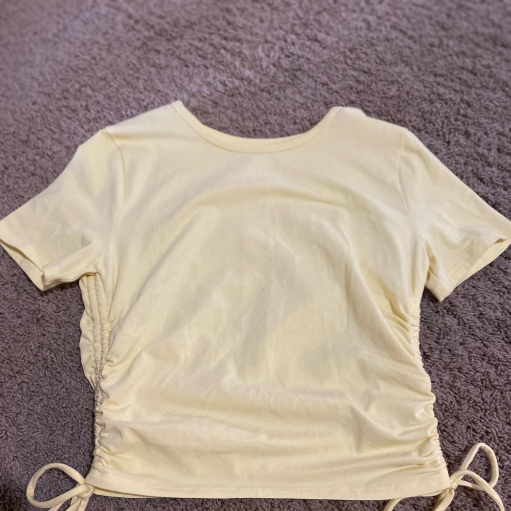 A yellow baby tee with string ties on the side